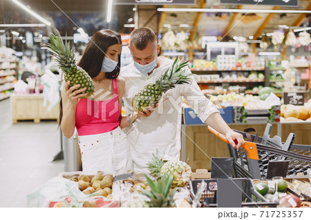 Couple in a medical masks in a supermarket Couple in a medical masks in a supermarket 71725357