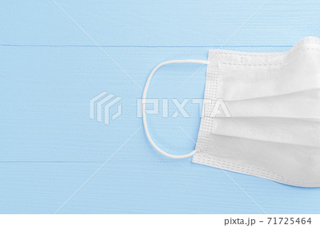 Medical protective white mask on a wooden light blue background. Half. Copyspace. Close-up. Coronavirus Remedies Concept 71725464