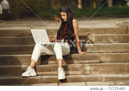 Woman in a summer park with a laptop 71725465