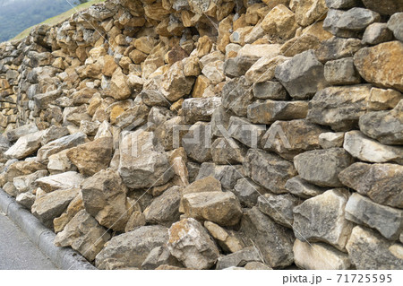 Destroyed retaining stone wall of natural stone after heavy rains along the asphalt path Destroyed retaining stone wall of natural stone after heavy rains along the asphalt path 71725595