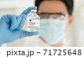 scientist in laboratory with bottle of covid-19 vaccine 71725648