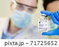 scientist in laboratory with bottle of covid-19 vaccine 71725652