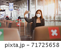 A passenger businesswoman wearing face mask doing selfie while waiting on boarding at the airport, lifestyle new normal customer after covid-19 pandemic. 71725658