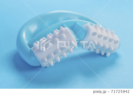 Turquoise plastic massager with white soft rollers and pimples on a blue creative background. Massage treatment for cellulite 71725942
