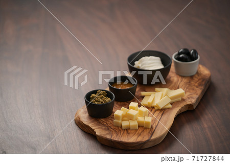 Wood board with cheese, olives and sauces on walnut table with copy space Wood board with cheese, olives and sauces on walnut table with copy space 71727844