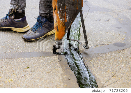 Sealing joint crack in asphalt road surface restoration work. 71728206