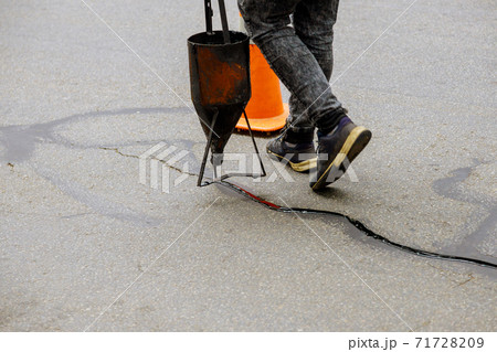 Sealing joint crack in asphalt road surface restoration work. 71728209