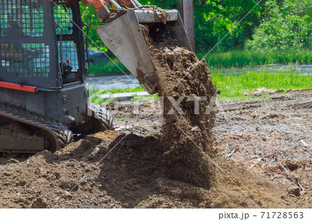 Bulldozer moving, leveling ground at construction site 71728563