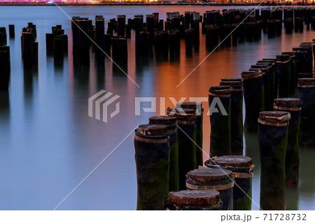 Long exposure at the Brooklyn Bridge Park in New York City across east river with wood pilings water Long exposure at the Brooklyn Bridge Park in New York City across east river with wood pilings water 71728732