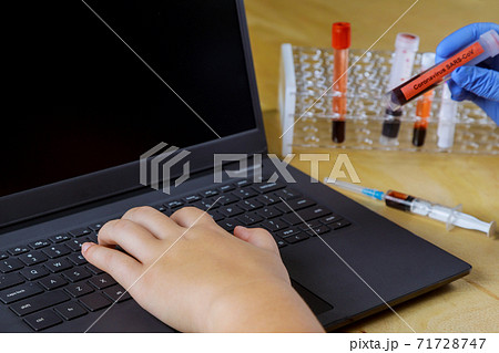 Doctor hand working with laptop computer in medical laboratory workspace medic holding blood sample tube Doctor hand working with laptop computer in medical laboratory workspace medic holding blood sample tube 71728747