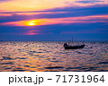 Little boat floating on the calm water under amazing sunset 71731964