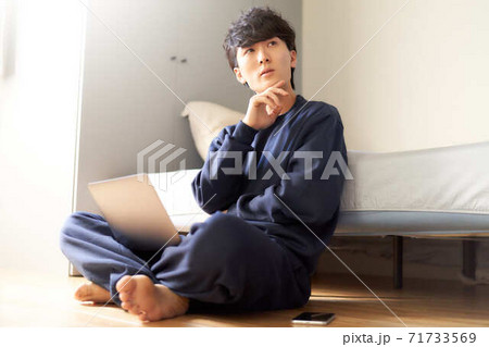 寝室でPCを膝に乗せて考え事をする男性 寝室でPCを膝に乗せて考え事をする男性 71733569