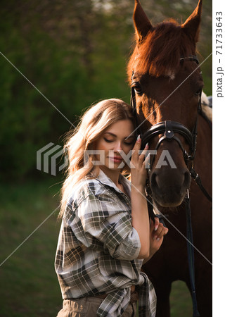 Beautiful girl with her horse and beautiful warm sunset in the spring forest. 71733643