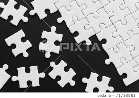 Unfinished white jigsaw puzzle pieces on black background Unfinished white jigsaw puzzle pieces on black background 71733983