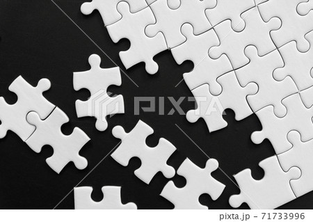 Unfinished white jigsaw puzzle pieces on black background 71733996