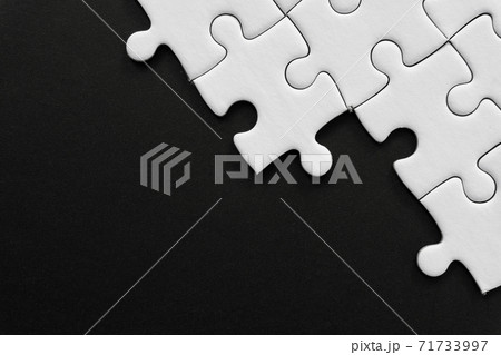 Unfinished white jigsaw puzzle pieces on black background with  copy space 71733997
