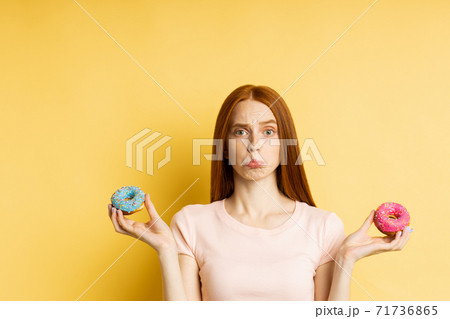 Young beautiful woman with doughnuts on yellow background 71736865