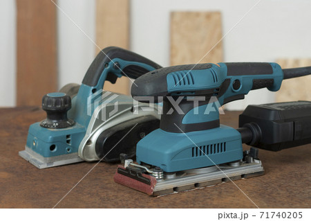 Electric planer and electric sheet finishing sander on old rusty metal sheet, on background oriented strand board Electric planer and electric sheet finishing sander on old rusty metal sheet, on background oriented strand board 71740205