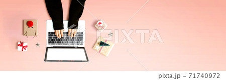 Person using a laptop computer with Christmas gift boxes 71740972