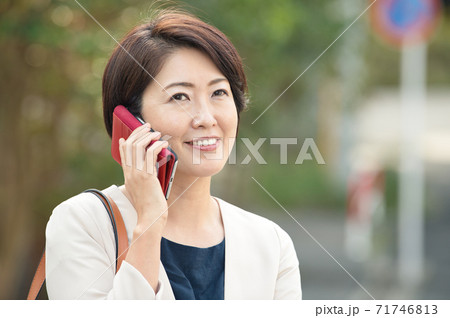 スーツを着てスマホで通話する日本人ビジネスウーマン 働く40代の女性の写真素材