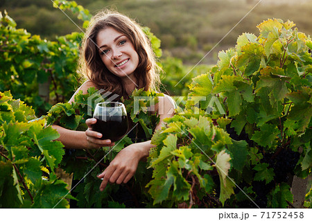 woman in green dress with a glass of wine in the garden of grapes 71752458