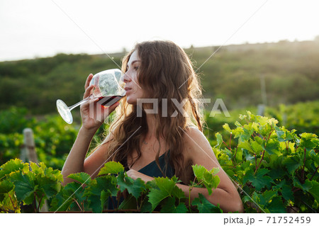 woman in green dress with a glass of wine in the garden of grapes woman in green dress with a glass of wine in the garden of grapes 71752459