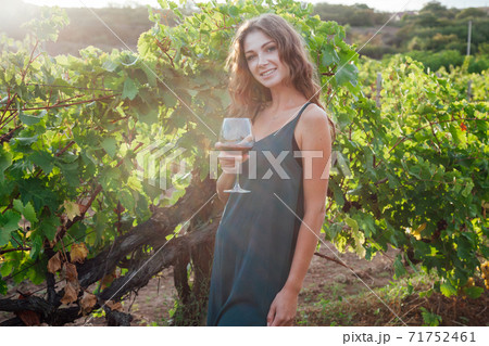 woman in green dress with a glass of wine in the garden of grapes woman in green dress with a glass of wine in the garden of grapes 71752461
