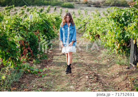 beautiful woman in white dress and denim jacket in the vineyards 71752631