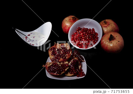 Pomegranates in wooden plate and seeds in bowl with yogurt Pomegranates in wooden plate and seeds in bowl with yogurt 71753655