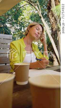 vertically. businesswoman holding video conference via laptop in an outdoor cafe 71754922