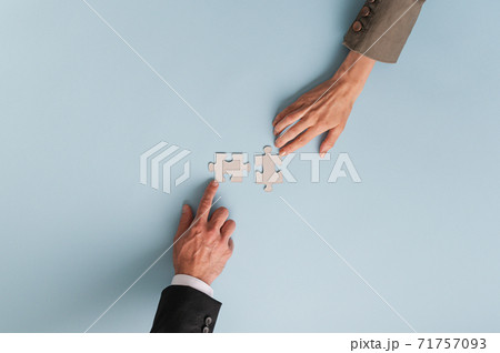 Top view of hands of businesswoman and businessman joining two  matching puzzle pieces 71757093