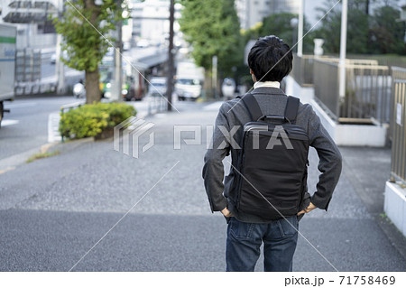 バックパックを背負った若い男性の後ろ姿の写真素材