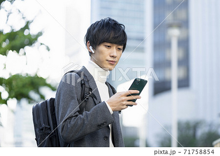 ヘッドホンをしてスマホの画面を見る若い男性 ヘッドホンをしてスマホの画面を見る若い男性 71758854