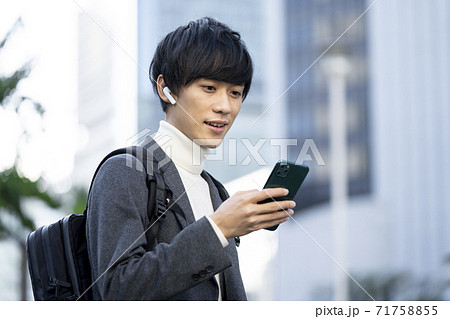 ヘッドホンをしてスマホの画面を見る若い男性 ヘッドホンをしてスマホの画面を見る若い男性 71758855