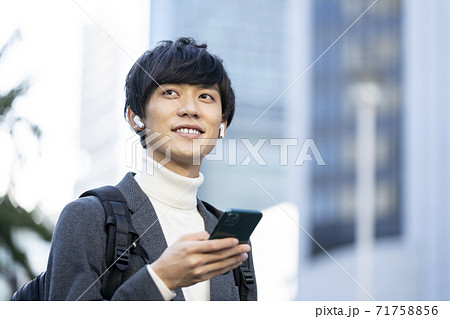 ワイヤレスヘッドホンをしてスマートフォンを持つ若い男性 71758856