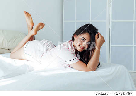 beautiful woman in striped pajamas in the bedroom on the bed beautiful woman in striped pajamas in the bedroom on the bed 71759767