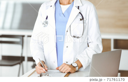 Unknown woman-doctor at work in clinic. Female physician controls medication history record and medical exam results, close-up. Medicine concept Unknown woman-doctor at work in clinic. Female physician controls medication history record and medical exam results, close-up. Medicine concept 71761170