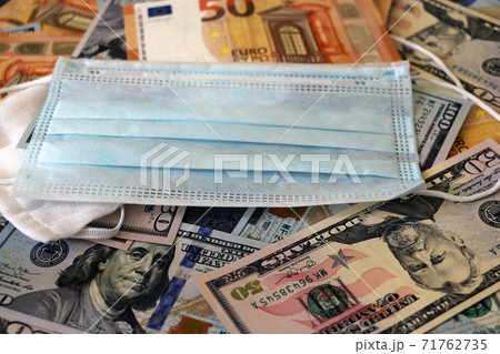 Medical mask on dollars and euro as a symbol of increasing prices for protecting the respiratory tract from the virus. There is a place for copyspace. 71762735