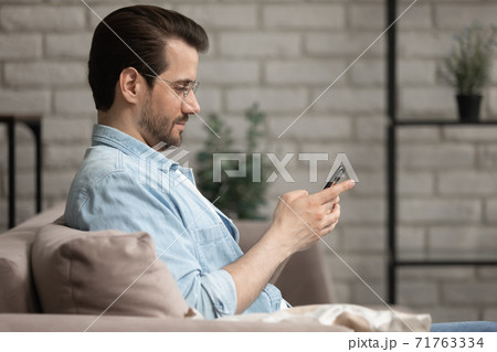 Addicted to technology young relaxed man using mobile applications. Addicted to technology young relaxed man using mobile applications. 71763334