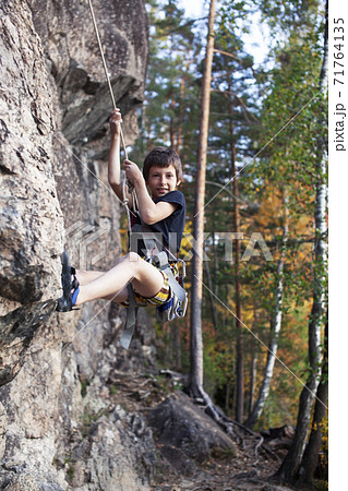 cute teen kid climbing on rock with insurance, lifestyle sport people concept cute teen kid climbing on rock with insurance, lifestyle sport people concept 71764135