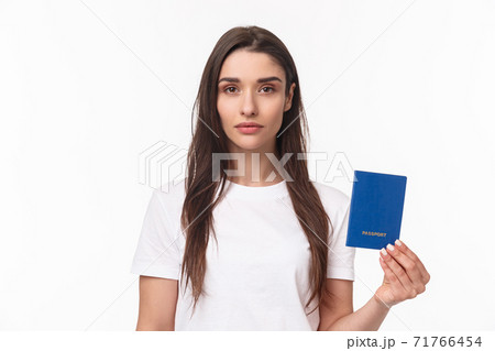 Travelling, holidays, summer concept. Serious-looking young confident girl showing her brand new passport, ready to travel abroad, packing up baggage, standing white background Travelling, holidays, summer concept. Serious-looking young confident girl showing her brand new passport, ready to travel abroad, packing up baggage, standing white background 71766454