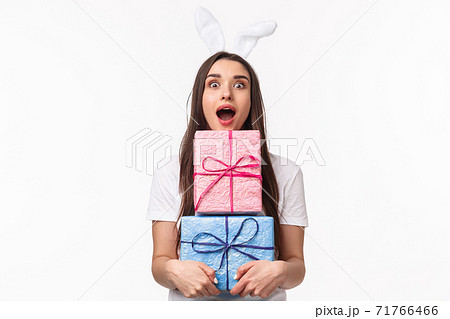 Celebration, holidays and presents concept. Portrait of amused young beautiful woman with rabbit ears, open mouth excited, holding packs of gifts, receiving awesome presents, white background Celebration, holidays and presents concept. Portrait of amused young beautiful woman with rabbit ears, open mouth excited, holding packs of gifts, receiving awesome presents, white background 71766466