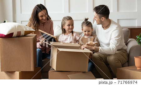 Family moved to new house sitting on couch unpacking belongings 71766974
