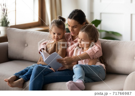 Mother reading interesting fairy tale story book to little daughters Mother reading interesting fairy tale story book to little daughters 71766987