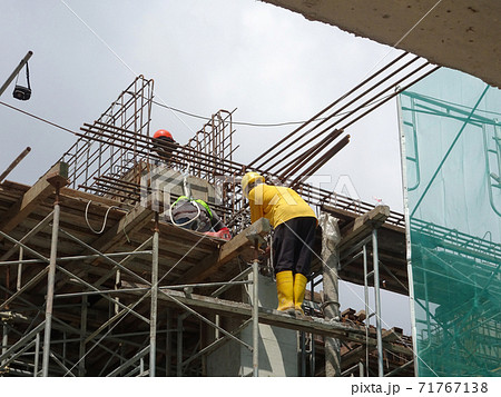 MALACCA, MALAYSIA -MARCH 2, 2020: Construction workers working at height install reinforcement bars at the construction site. They are supplied with harnesses and other safety equipment. 71767138