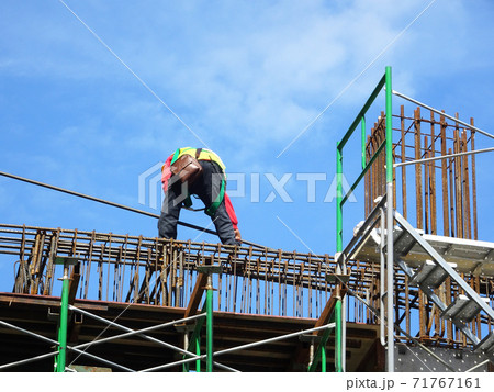 MALACCA, MALAYSIA -MARCH 2, 2020: Construction workers working at height install reinforcement bars at the construction site. They are supplied with harnesses and other safety equipment. 71767161