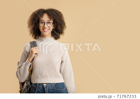 Smiling african american millennial woman in sweater in glasses with backpack looking at camera Smiling african american millennial woman in sweater in glasses with backpack looking at camera 71767233