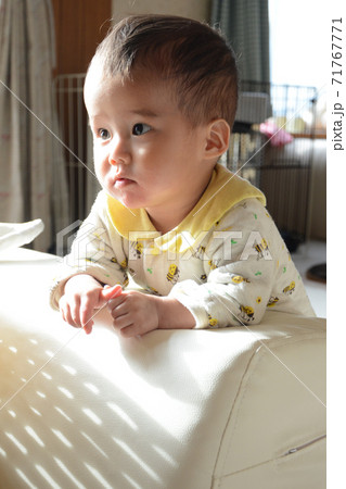 つかまり立ちでテレビを見る赤ちゃんの写真素材