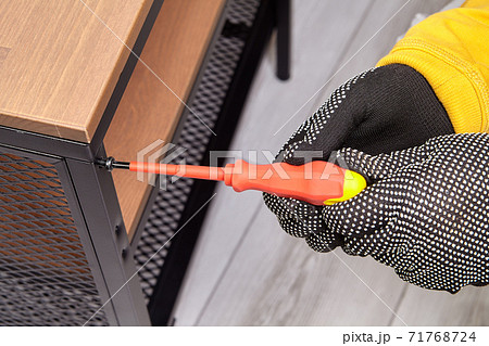 Handyman is assembling flat pack TV stand using screwdriver. 71768724