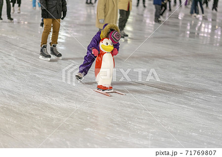 Ice rink. Little child holds a penguin for support and learn to skate. Happy childhood and Winter activities Ice rink. Little child holds a penguin for support and learn to skate. Happy childhood and Winter activities 71769807